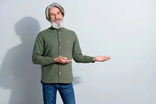 Retrato de atractivo hombre de pelo gris alegre demostrando espacio de copia nueva solución aislada sobre fondo de color pastel gris —  Fotos de Stock