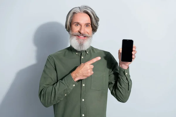 Yakışıklı, modaya uygun, neşeli, gri saçlı bir adamın portresi. Gri pastel arka planda izole edilmiş cihazın fotokopi alanı reklamını gösteriyor. — Stok fotoğraf