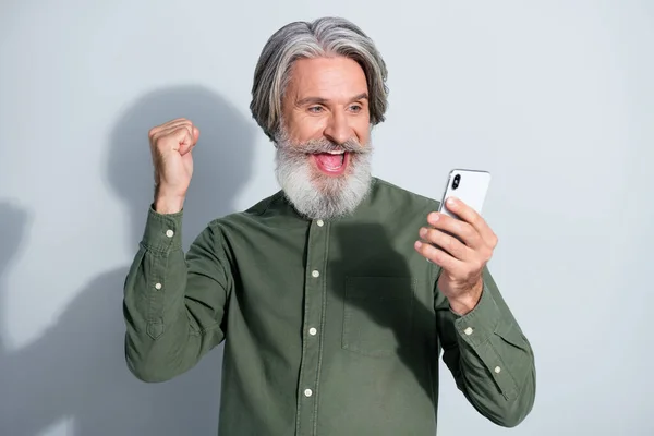 Portret van aantrekkelijke vrolijke gelukkig grijs-harige man met behulp van apparaat verheugen als volgen geïsoleerd over grijs pastel kleur achtergrond — Stockfoto