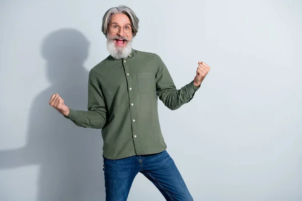 Фото счастливчика пенсионера, одетого в рубашку цвета хаки, кричащего кулаками на изолированном сером фоне — стоковое фото