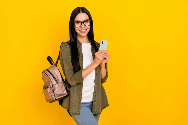 Fénykép vicces fiatal hölgy tartsa telefon viselet táska szemüveg ing elszigetelt sárga háttér — Stock Fotó