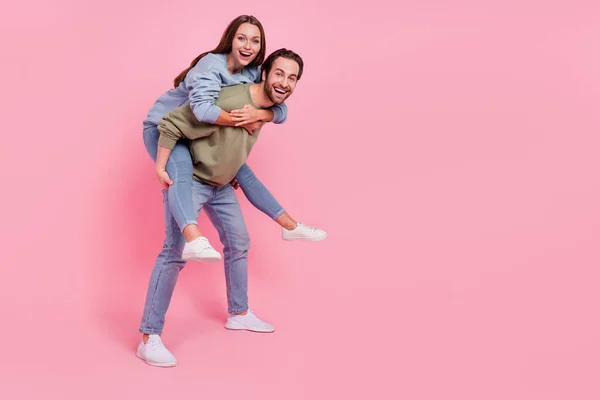 Perfil de corpo inteiro retrato de duas pessoas despreocupadas transportar piggyback desfrutar de tempo livre isolado no fundo cor-de-rosa — Fotografia de Stock