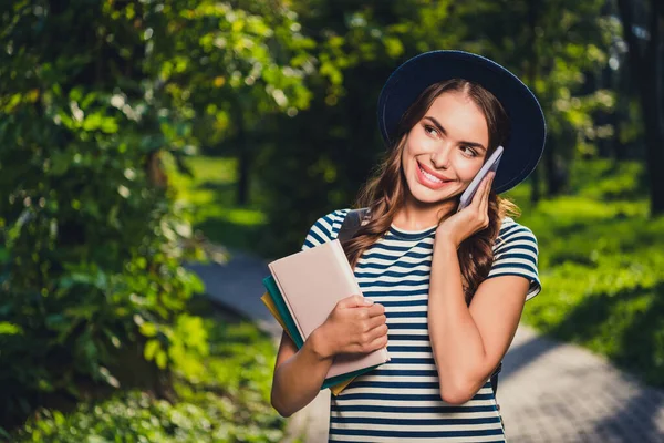 Retrato de belo alegre bonito menina segurando livro falando no telefone discutindo passatempo ao ar livre — Fotografia de Stock