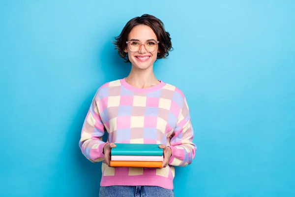 Foto de la bella dama milenaria morena sostener libro usar gafas suéter a cuadros aislado sobre fondo azul —  Fotos de Stock