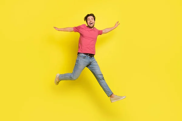 노란색 배경에 고립된 빨간 티셔츠 청바지를 입고 달리는 젊은 남자의 전신 사진 — 스톡 사진