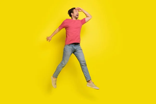 Foto in voller Größe von beeindruckt Brunet Millennial Kerl Sprung tragen rote T-Shirt Jeans Turnschuhe isoliert auf gelbem Hintergrund — Stockfoto