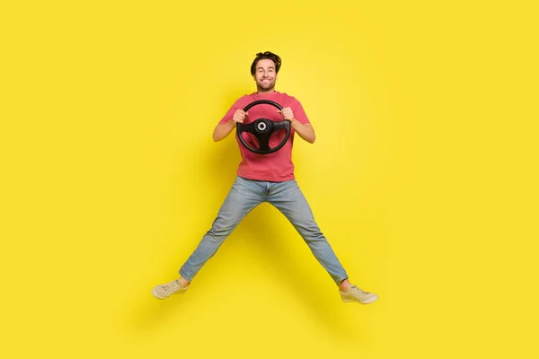 Pleine taille photo de belle barbe jeune gars conduire saut porter rouge t-shirt jeans chaussures isolées sur fond jaune — Photo