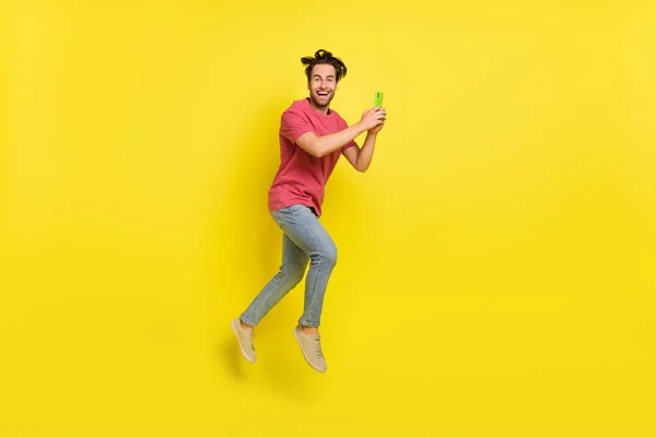 Full body profile photo of cool beard young guy run hold telephone wear red t-shirt jeans chaussures isolées sur fond jaune — Photo