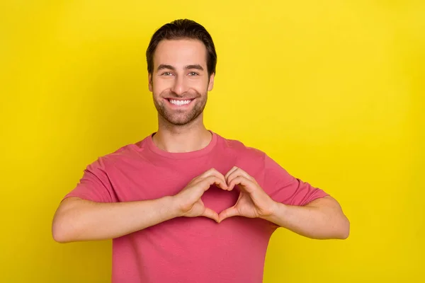 Foto de hombre romántico manos demuestran símbolo del corazón desgaste rosa camiseta aislado color amarillo fondo — Foto de Stock