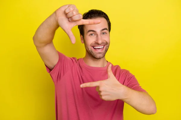 Photo of funny cheerful guy make frame gesture prepare shoot picture wear pink t-shirt isolated yellow color background — Stock Photo, Image