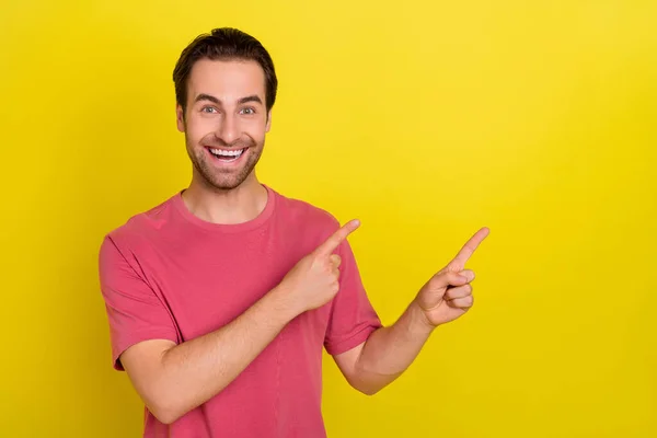 Foto de chico confiable emocionado indican dedo índice vacío espacio venta desgaste rosa camiseta aislado color amarillo fondo — Foto de Stock