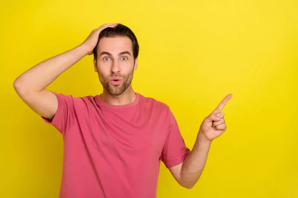 Фото смешного положительного парня руки голову прямой палец пустое пространство omg лицо носить розовую футболку изолированный желтый цвет фона — стоковое фото