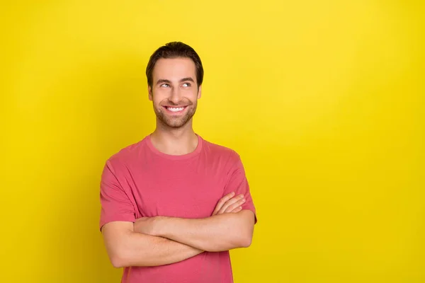 Foto de tipo curioso positivo cruzó los brazos mirada espacio vacío desgaste rosa camiseta aislado color amarillo fondo — Foto de Stock