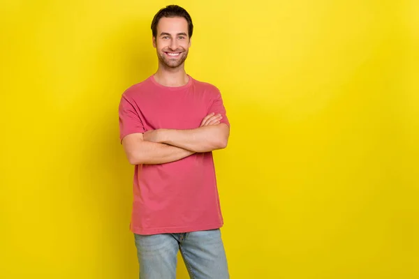 Zdjęcie pozytywne zadowolony facet składane ręce promieni uśmiech nosić różowy t-shirt dżinsy izolowane żółty kolor tło — Zdjęcie stockowe
