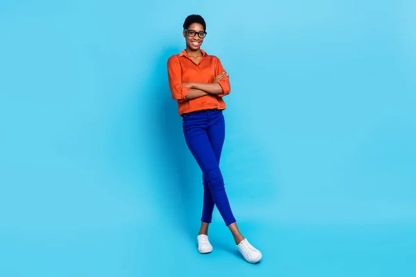 Foto de la empresa inteligente positiva representante dama brazos doblados desgaste gafas camisa marrón aislado color azul fondo —  Fotos de Stock