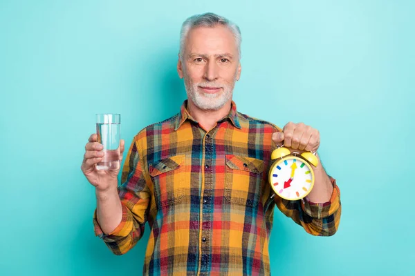 Foto de hombre positivo pensionista vestido camisa a cuadros agua potable celebración reloj aislado color verde azulado fondo —  Fotos de Stock