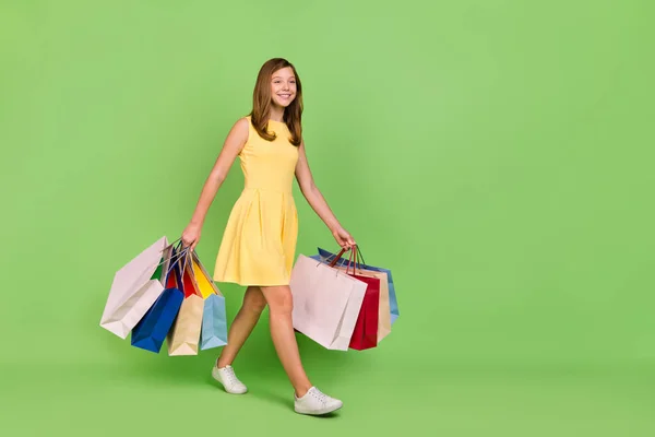 フルサイズの写真の愛らしい正の女の子見てコピースペース外出先ショッピングホールド多くのバッグ隔離された緑の色の背景 — ストック写真
