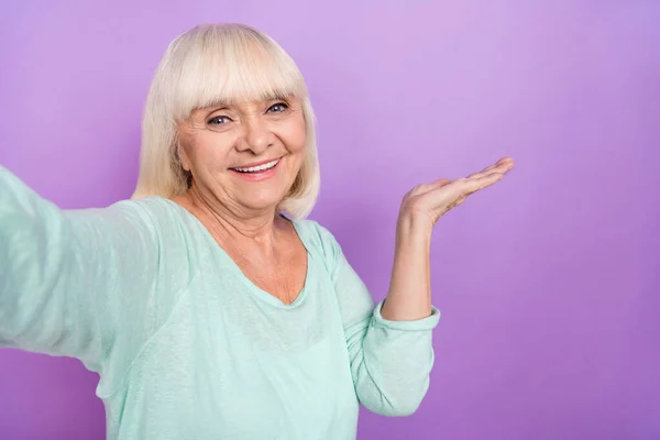 Фото веселої гостинної леді, яка стріляє рукою селфі, демонструє порожній простір носити сорочку для сліз ізольований фіолетовий кольоровий фон — стокове фото