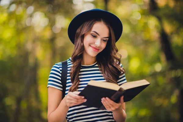 Портрет привлекательной веселой целеустремленной девушки, наслаждающейся чтением интересной книги на свежем воздухе — стоковое фото