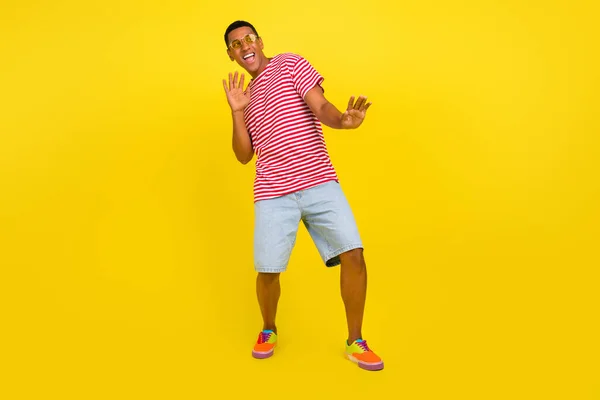 Foto de tamaño completo de chico dinámico viaje de baile discoteca usar ropa de rayas rojas aisladas sobre el brillo de fondo de color amarillo —  Fotos de Stock