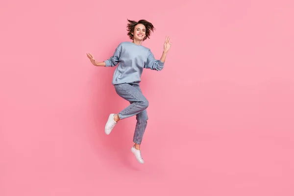 Plná délka fotografie cool tisícileté dáma skok vlna oblečení jumper džíny obuv izolované na růžovém pozadí — Stock fotografie