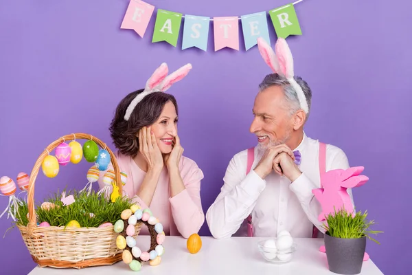 Portret dwóch zabawnych starszych partnerów siedzieć stół patrzeć na siebie przygotować wydarzenie izolowane na fioletowym tle koloru — Zdjęcie stockowe