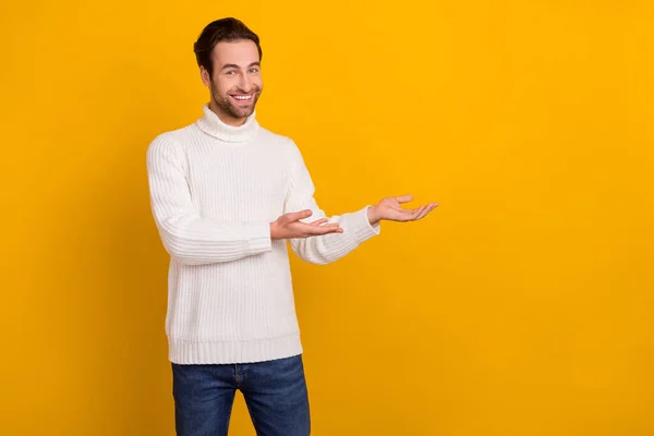 Foto de encantador chico lindo usar jersey blanco sonriendo invitando a los brazos espacio vacío aislado color amarillo fondo — Foto de Stock