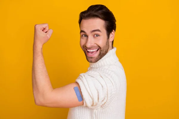 Foto van zelfverzekerde gelukkige man tonen hand lijm verband verhogen vuist slijtage witte trui geïsoleerde gele kleur achtergrond — Stockfoto