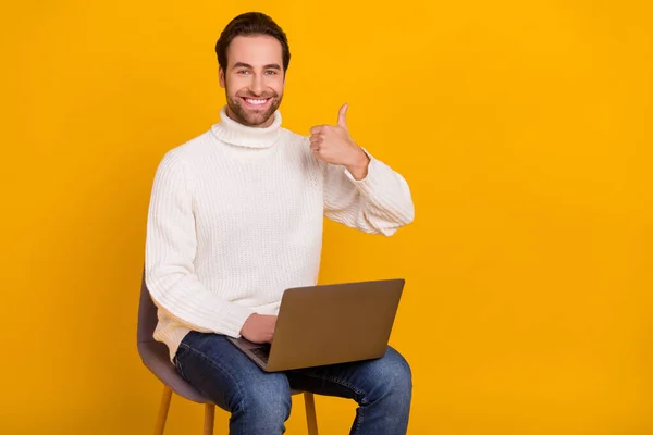Фото надійного віддаленого працівника сидячого крісла тримайте ноутбук, піднімайте великий палець вгору, одягніть білий светр ізольований жовтий колір фону — стокове фото