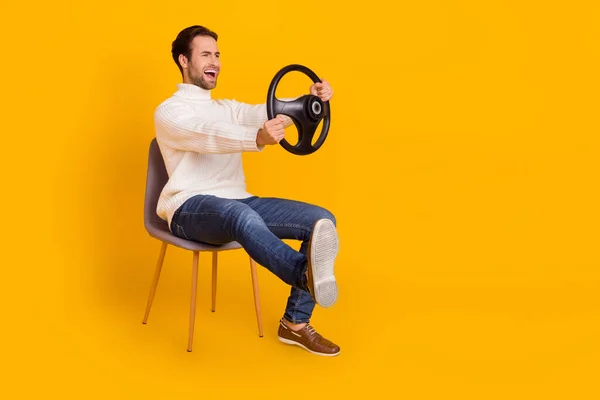 Beyaz süveter giyen, araba süren, bacağını iten adamın fotoğrafı. Kırık sarı arka plan. — Stok fotoğraf