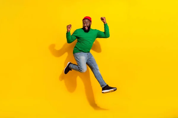 Foto de loco buen chico confiado salto regocijo éxito desgaste rojo gorro verde camisa aislado amarillo color fondo — Foto de Stock