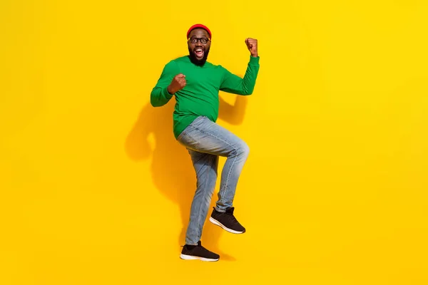 Foto de feliz hombre exitoso celebrar victoria desgaste especificaciones rojo gorro verde camisa aislado amarillo color fondo — Foto de Stock