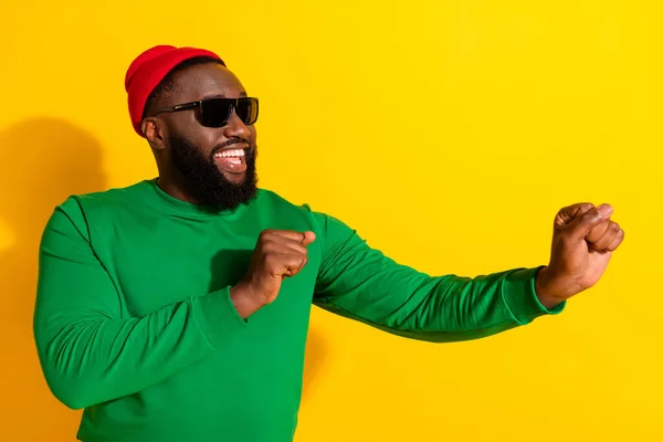 Photo of positive nice man dance wygląd pusty przestrzeń nosić sunglass czerwony czapka zielony koszula odizolowany żółty kolor tło — Zdjęcie stockowe