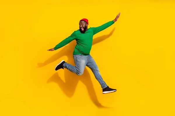 Zdjęcie beztroski inspirowane wesoły facet skakać płaszczyzna pozować nosić czerwony czapka zielony koszula odizolowany żółty kolor tło — Zdjęcie stockowe