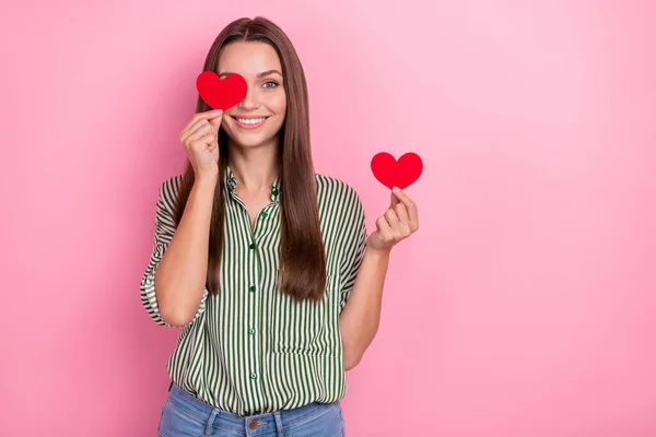 Photo of cheerful lady cover eye red heart beaming smile wear striped green shirt isolated pink color background — Stock Photo, Image