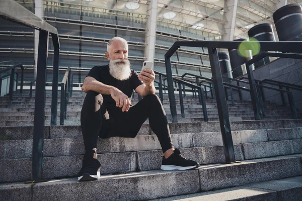 Pleine longueur vue de la taille du corps de viril homme aux cheveux gris retraité attrayant assis sur des escaliers en pierre à l'aide dispositif gadget bavarder à l'extérieur — Photo