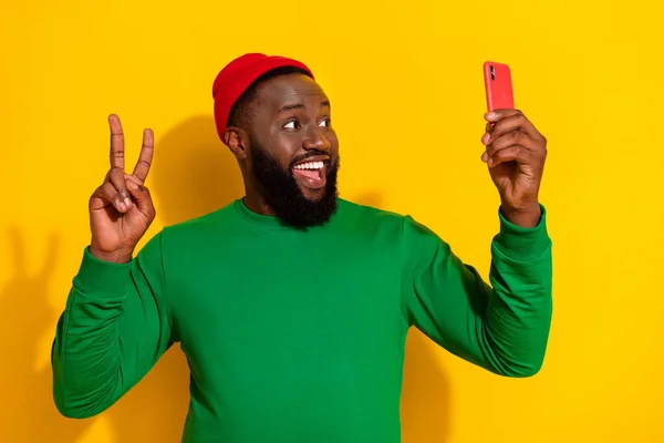Portrét atraktivní trendy veselý chlap, přičemž selfie ukazuje V-znak izolované přes jasně žluté barvy pozadí — Stock fotografie