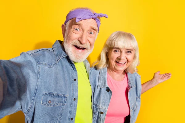 Foto de marido retirado funky esposa usar jeans ropa tacking selfie invitando aislado color amarillo fondo —  Fotos de Stock