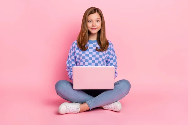 Foto de tamaño completo de marrón chica adolescente agradable sentarse tipo portátil usar suéter jeans calzado aislado sobre fondo rosa —  Fotos de Stock