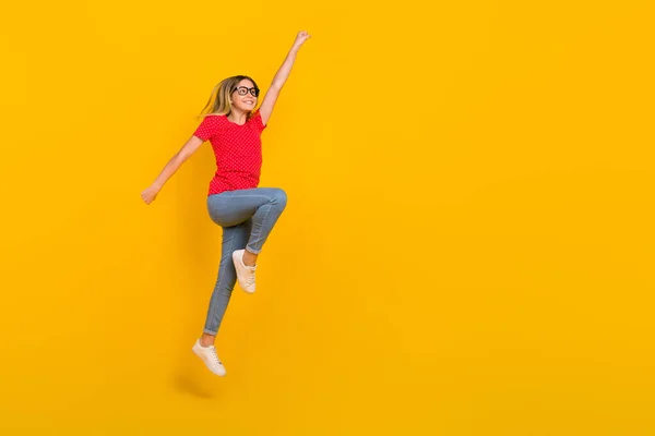 Foto lateral de perfil de cuerpo completo de la joven activa salto héroe de poder mirar espacio vacío aislado sobre fondo de color amarillo —  Fotos de Stock