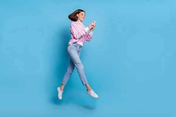 Full length photo of cute young lady run with telephone wear shirt jeans obuwie izolowane na niebieskim tle — Zdjęcie stockowe