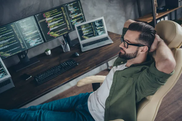 Fotografie unaveného zasněného mladého muže nosit zelené košile brýle s odpočinkem pracovní pauza ruce za hlavou vnitřní dílny pracoviště — Stock fotografie