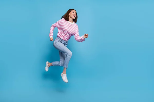 フルサイズの写真のクールな若い女性ランウェアシャツジーンズスニーカー隔離された青の背景 — ストック写真