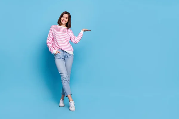 Foto de tamaño completo de optimista milenial dama stand hold promo desgaste camisa jeans zapatos aislados sobre fondo azul —  Fotos de Stock