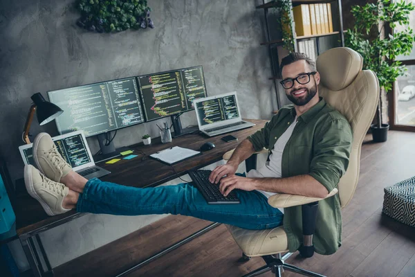 Foto van vrolijk goed humeur jonge man gekleed kaki shirt bril codering programma modern gadget binnen workshop werkplek — Stockfoto