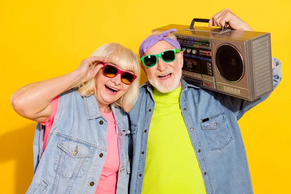 Foto van leuke opgewonden echtgenoot vrouw dragen jeans shirts donker brillen luisteren boombox geïsoleerde gele kleur achtergrond — Stockfoto