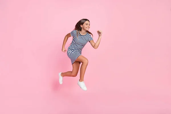 Zdjęcie dość słodkie dziewczyna ubrana w paski sukienka runnig puste miejsce skacząc wysoki odizolowany różowy kolor tła — Zdjęcie stockowe