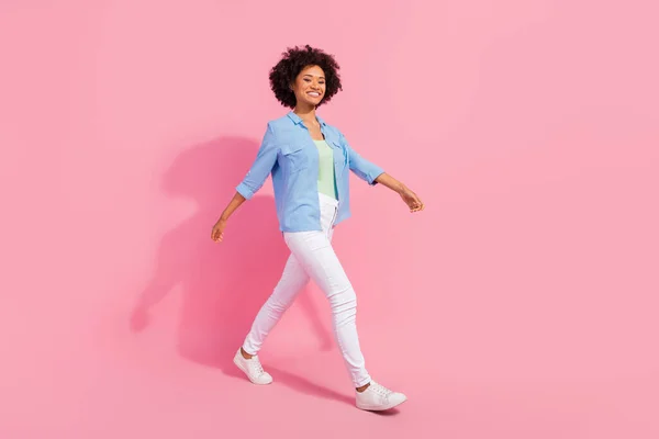 Foto av positiva vackra dam promenad gå framåt bära denim skjorta byxor sneakers isolerad rosa färg bakgrund — Stockfoto