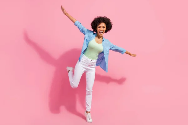 Foto de alegre despreocupado inspirado senhora ficar perna avião pose fazer asas usar camisa jeans isolado cor rosa fundo — Fotografia de Stock