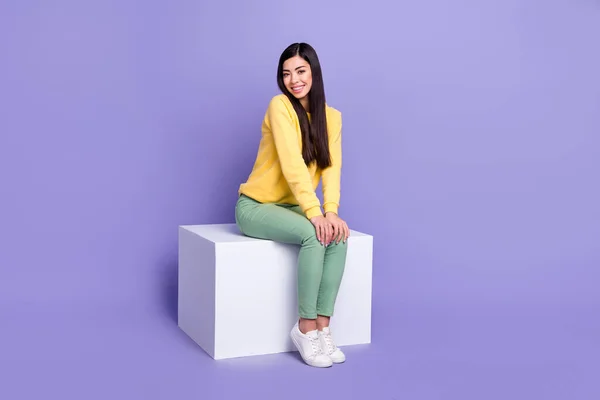 若いです明るい女の子座っているプラットフォームプロモーター着用カジュアル服隔離された上に紫色の背景 — ストック写真